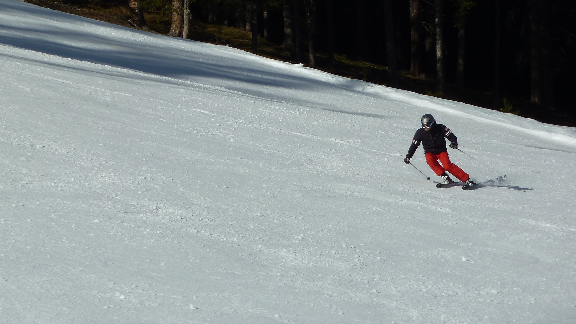 Ski guide watching a guest carve a turn on a quiet red run